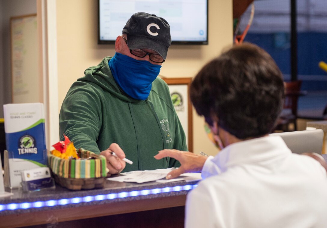 Douglas Coy, Tennis Club manager, checks a customer in, Nov 1, 2021, inside the Tennis Club at Wright-Patterson Air Force Base, Ohio. The club offers 4 LED lit courts and courses for kids or adult beginners in addition to a tennis cardio nights. (U.S. Air Force photo by Wesley Farnsworth)