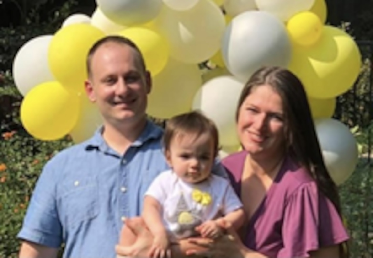 Cmdr. Jeff Padilla (left) poses with his wife Beth (right) and their child Elena celebrating Elena’s first birthday.