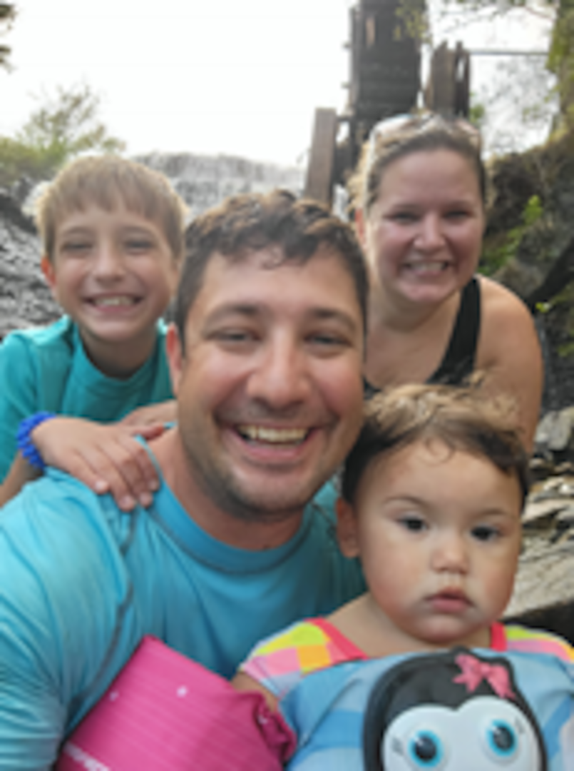 Petty Officer 2nd Class, Justin T. Harris (center), is pictured with his wife Sarah (top right) and their family during outdoor fun.