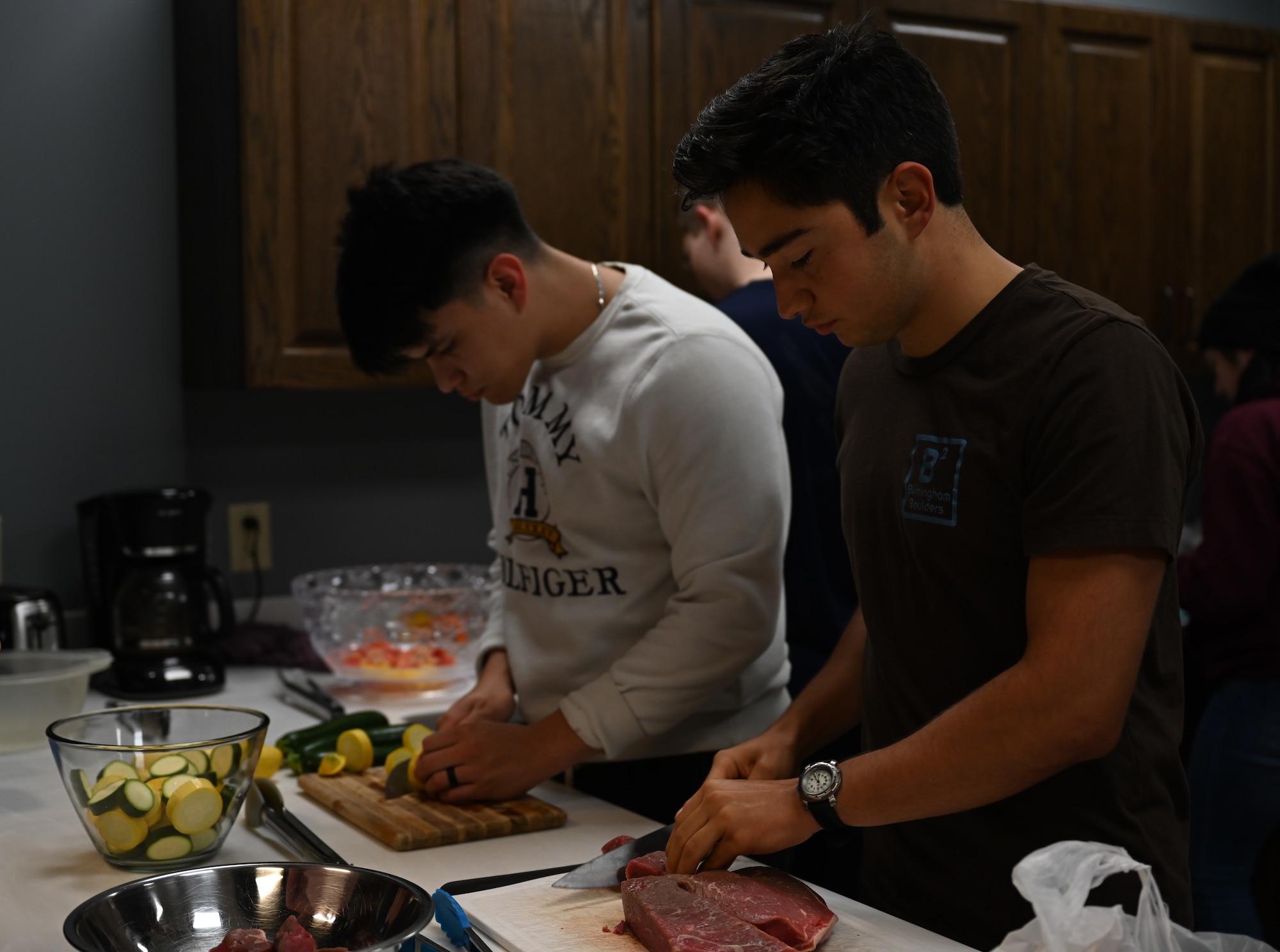 U.S. Air Force Airman 1st Class Miles Painter, 14th Operations Support Squadron (OSS) Aerospace Physiology technician and Airman Diego Valadez, 14th OSS Aircrew Flight Equipment technician, cut food to be used on kabobs, during a cooking class, Nov. 5, 2021, on Columbus Air Force Base, Miss. The base does not have a dining facility so it is important that Airmen learn how to safely and efficiently prepare their own meals. (U.S. Air Force photo by Airman 1st Class Jessica Haynie)
