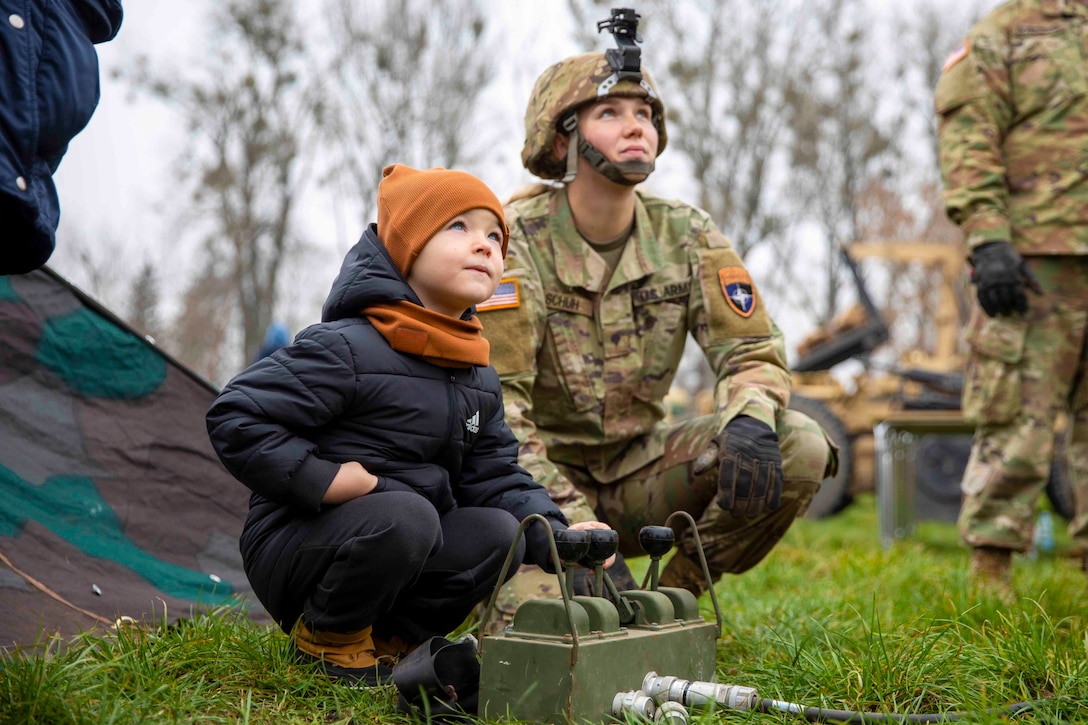 A soldier kneels next to a child.