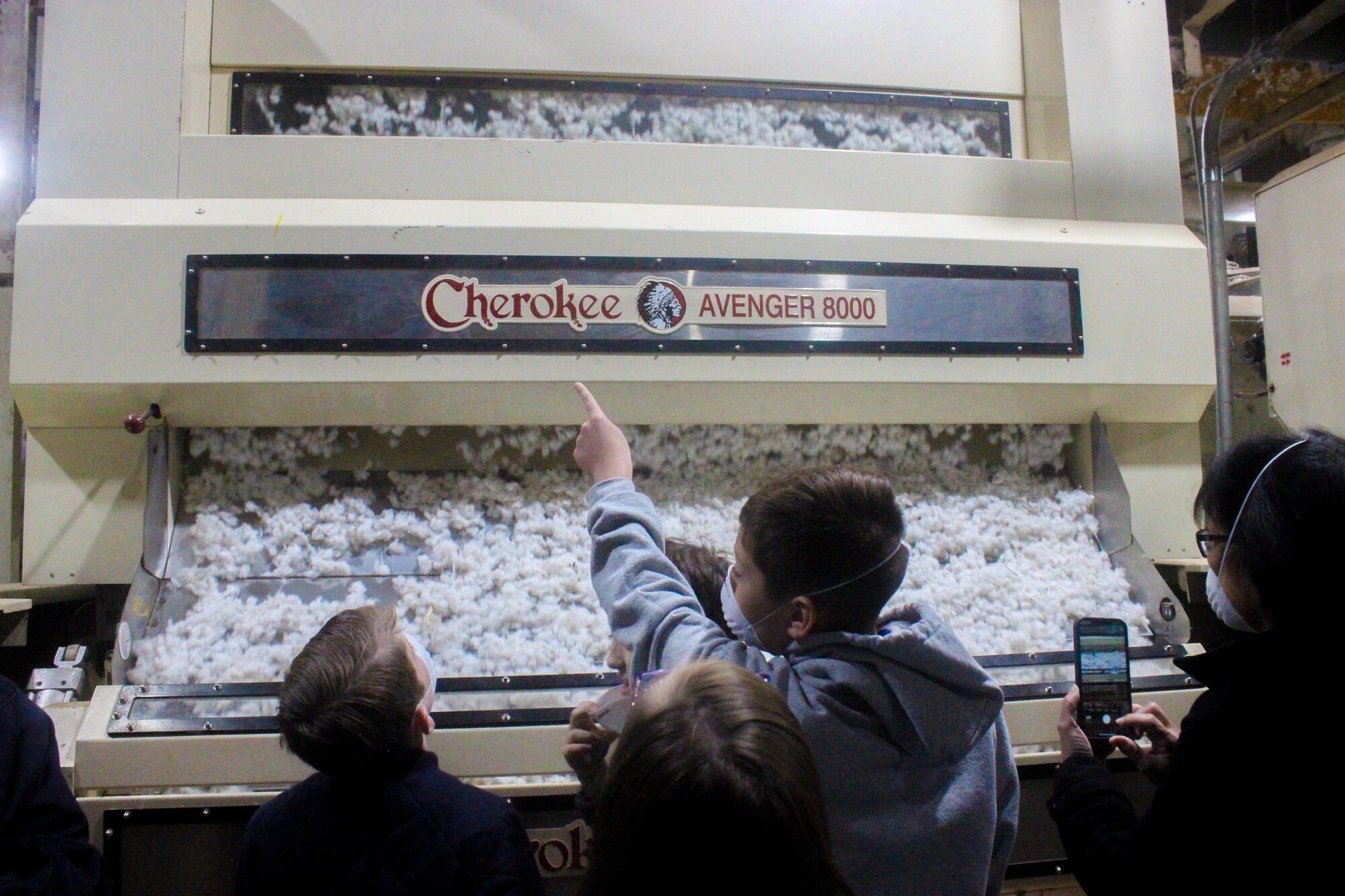 Children watch a cotton gin strip cotton