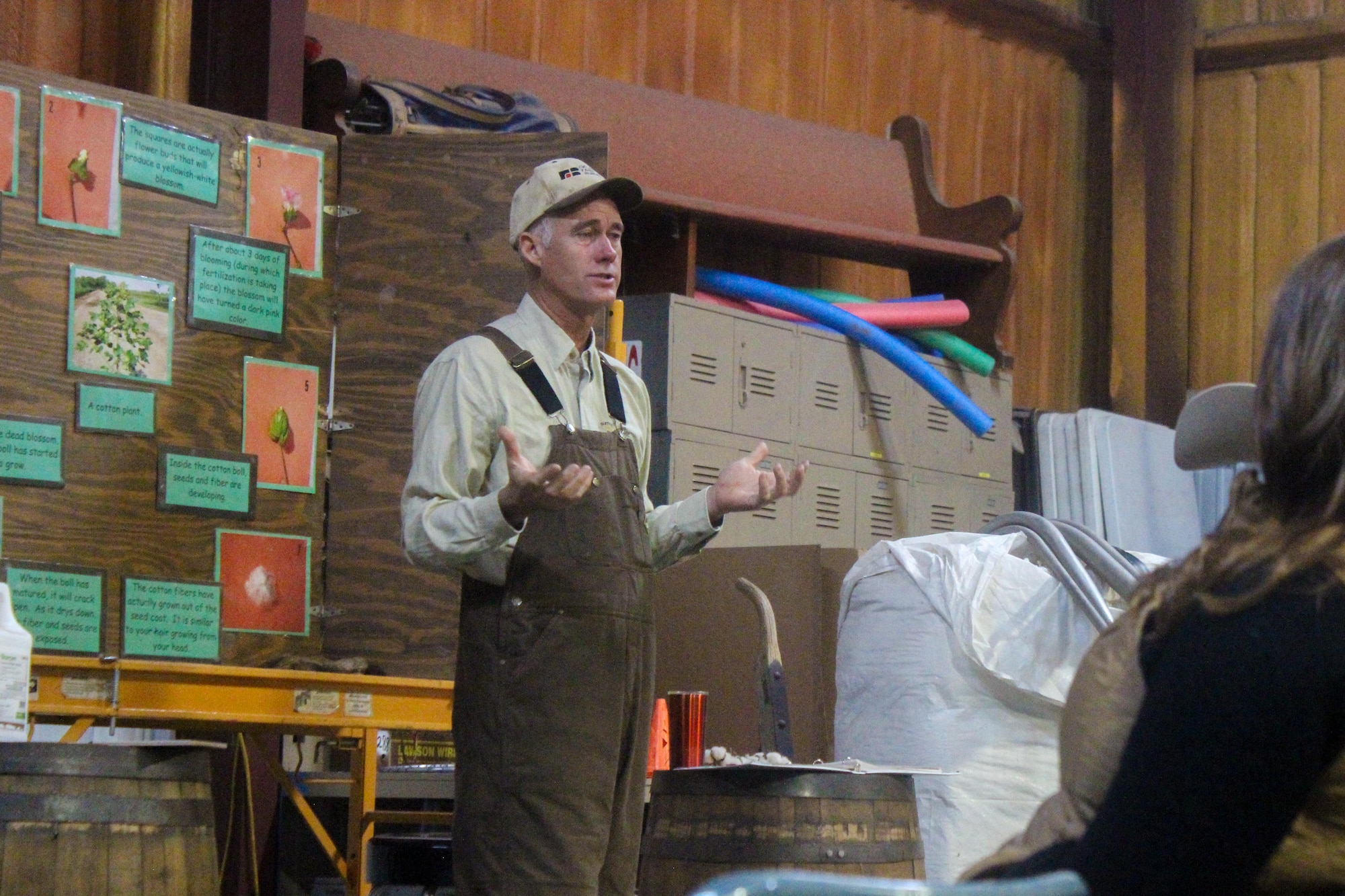 Man speaks to group in front of a poster board detailing the life cycle of cotton