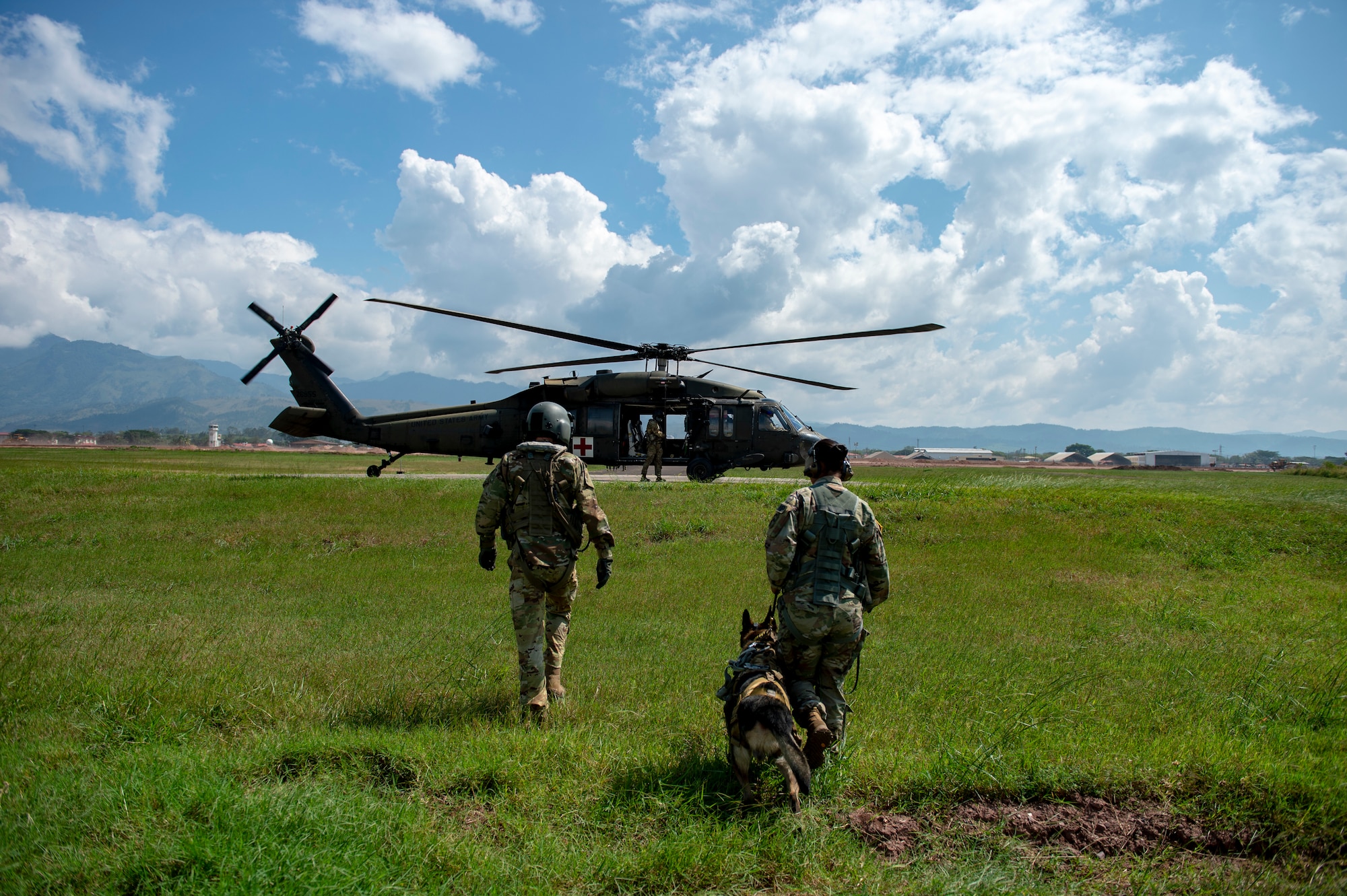 U.S. Army Spc. Kayla Garcia, a military working dog (MWD) handler assigned to Army Forces Battalion, Joint Task Force Bravo, and MWD Zoli walk with Sgt. Matthew Lynch, paramedic with the 1st Battalion, 228th Aviation Regiment Charlie Company, toward a UH-60 Blackhawk during hoist training at Soto Cano Air Base, Honduras, Oct. 29, 2021.