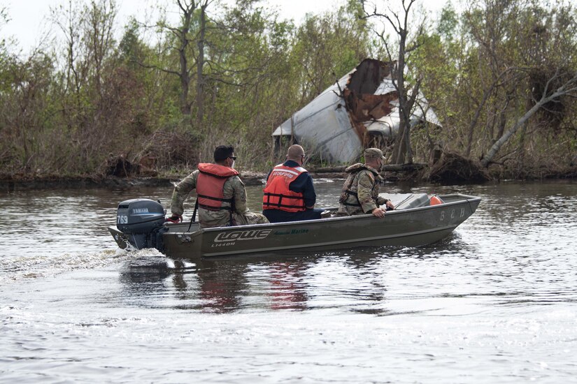 Service members ride in a small boat assessing damage.