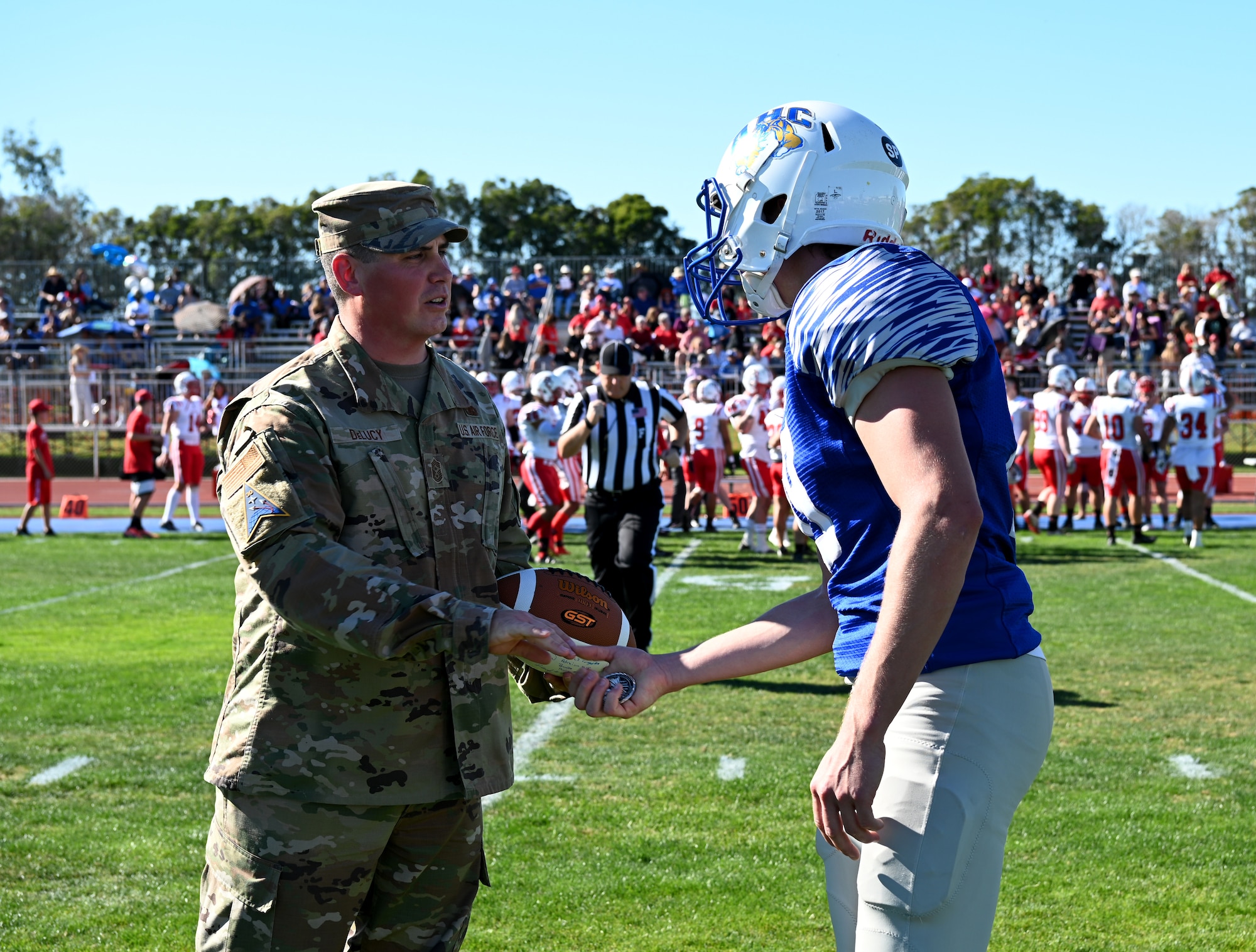 Chief Master Sgt. Jason DeLucy, Space Launch Delta 30 command chief, gifts Colton Theaker, a kicker for the Allan Hancock College Bulldogs Nov. 13, 2021, Santa Maria, Calif. DeLucy showed his appreciation by presenting a challenge coin to Theaker before the start of the game. (U.S. Space Force photo by Airman First Class Tiarra Sibley)