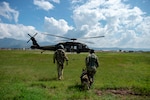 U.S. Army Spc. Kayla Garcia, a military working dog (MWD) handler assigned to Army Forces Battalion, Joint Task Force Bravo, and MWD Zoli walk with Sgt. Matthew Lynch, paramedic with the 1st Battalion, 228th Aviation Regiment Charlie Company, toward a UH-60 Blackhawk during hoist training at Soto Cano Air Base, Honduras, Oct. 29, 2021.