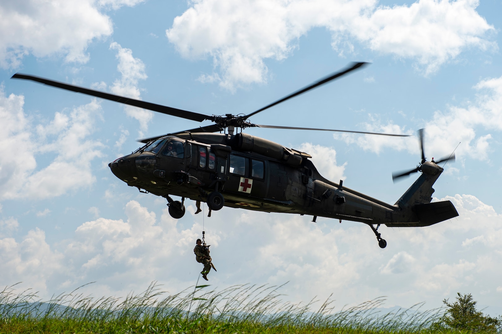 U.S. Army Spc. Kayla Garcia and military working dog (MWD) Zoli are hoisted from a UH-60 Blackhawk from the 1st Battalion, 228th Aviation Regiment Charlie Company, during a MWD hoist training exercise at Soto Cano Air Base, Honduras, Oct. 29, 2021.
