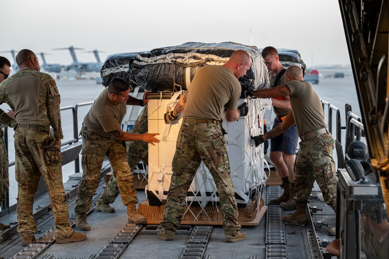 Members assigned to the 779th Expeditionary Airlift Squadron and 8th Expeditionary Air Mobility Squadron load cargo to be air-dropped into a C-130H Hercules at Al Udeid Air Base, Qatar, Oct. 31, 2021.