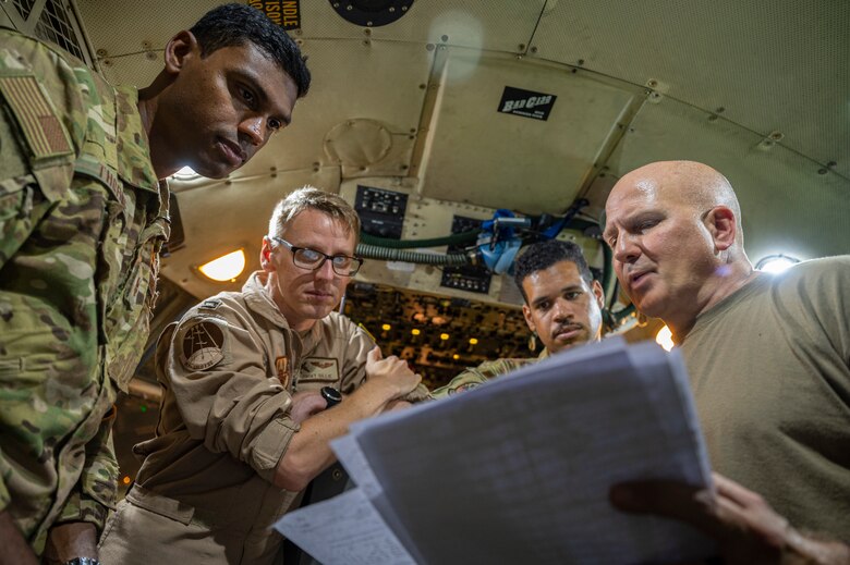 Crew members assigned to the 779th Expeditionary Airlift Squadron discuss flight plans on a C-130H Hercules at Al Udeid Air Base, Qatar, Oct. 31, 2021.
