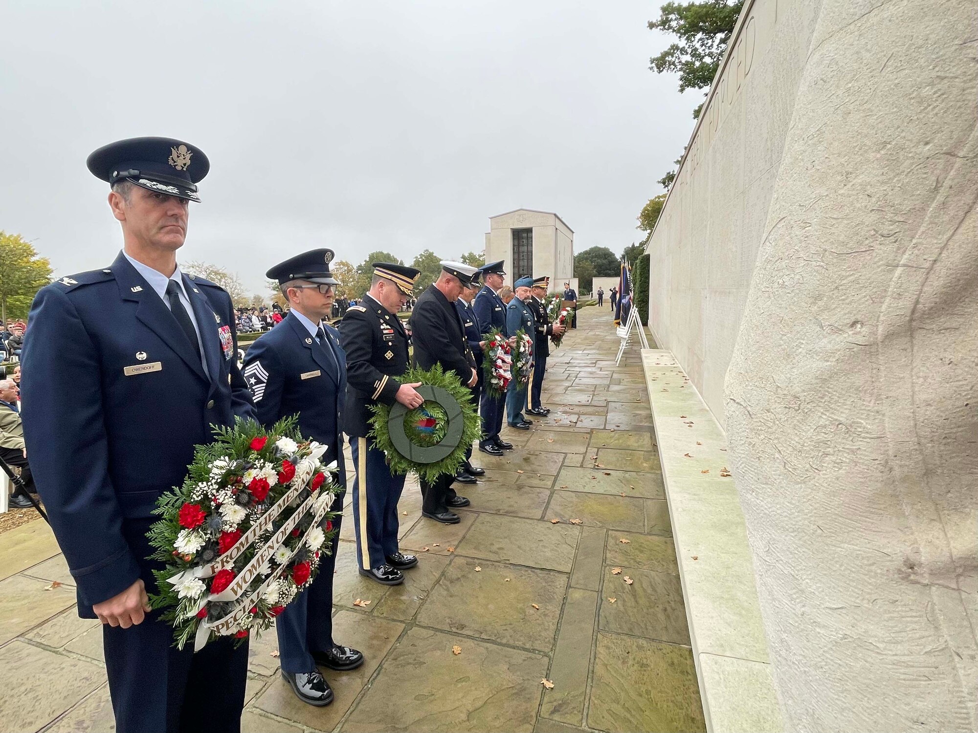 A group of U.S., Canada, and Royal Air Force servicemembers stand during a moment of silence to honor deceased military veterans, Cambridge, England, Nov. 11, 2021.Distinguished visitors and veterans were invited to participate in the ceremony by placing wreathes along the Tablets of the Missing. (U.S. Air Force photo by Senior Airman Joseph Barron).