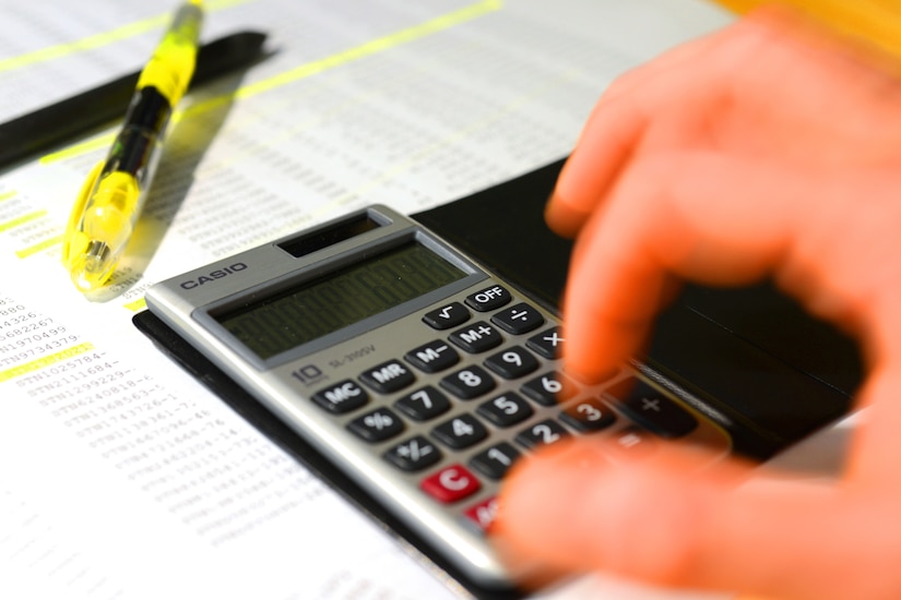 A hand types on a calculator.