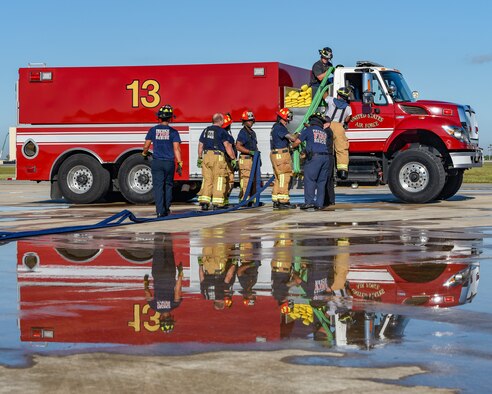 Firefighters assigned to the 60th Civil Engineer Squadron at Patrick Space Force Base, Fla., retrieve a hose after a simulated aircraft fire exercise at Patrick SFB Nov. 3, 2021. Simulated aircraft fires are held annually to help firefighters maintain certifications and prepare for emergency situations. (U.S. Space Force photo by Airman 1st Class Dakota Raub)