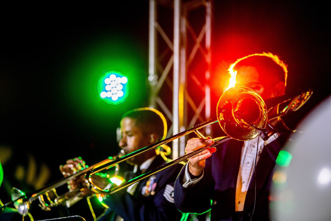 Members of a military band play instruments on a stage.