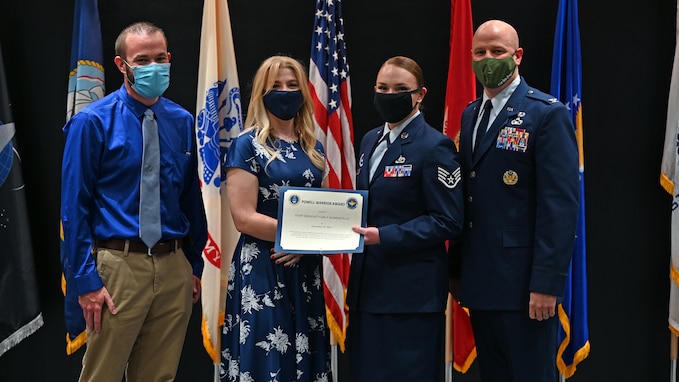 The granddaughter of the late retired Col. Charles Powell, Caitlin Cannady, presents the Powell Warrior Award to U.S. Air Force Staff Sgt. Carly Silberschlag, 316th Training Squadron instructor, at the Community College of the Air Force graduation in the Powell Event Center, Nov. 10, 2021. The award is presented only to CCAF graduates who display the highest degree of military excellence. (U.S. Air Force photo by Senior Airman Ethan Sherwood)