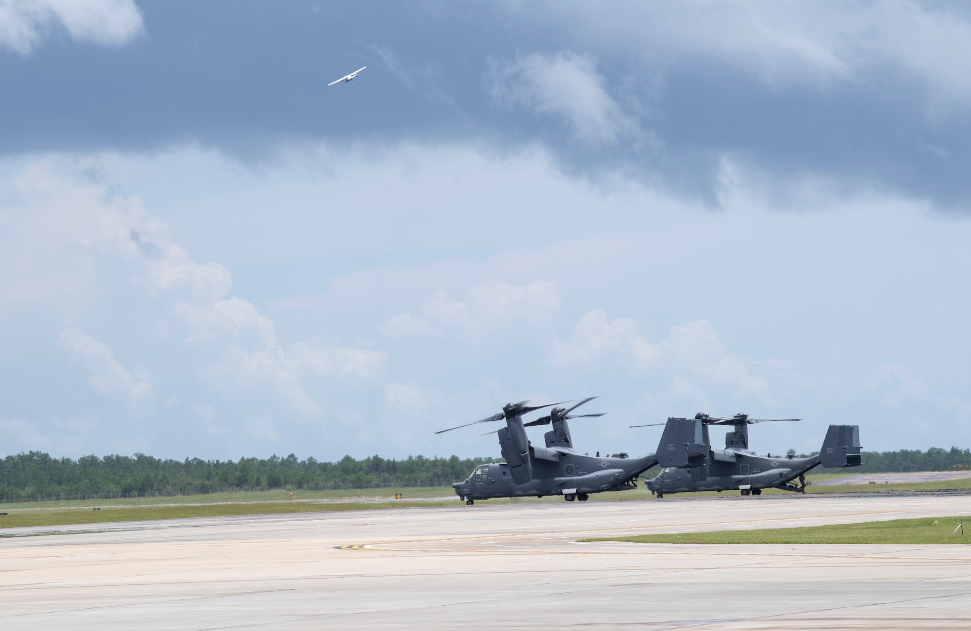 Two CV-22 Osprey park on the flightline as a C-146A Wolfhound flies overhead, at Duke Field, Florida, July 21, 2021. Air Force Special Operations Command leverages capabilities like FARP to ensure Airmen have multiple tools to accomplish a refueling mission in any environment, no matter how austere. (U.S. Air Force photo by Staff Sgt. Janiqua P. Robinson)