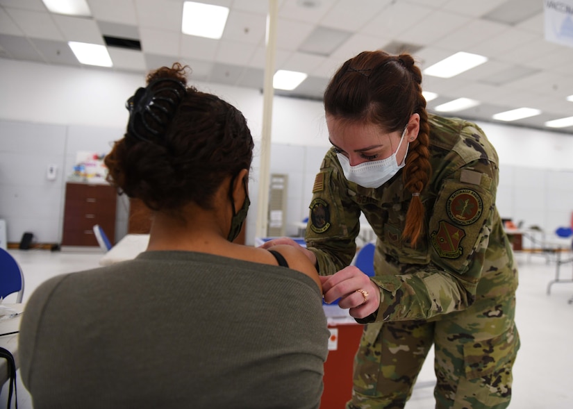 Airman puts a band-aid on a patient’s arm.