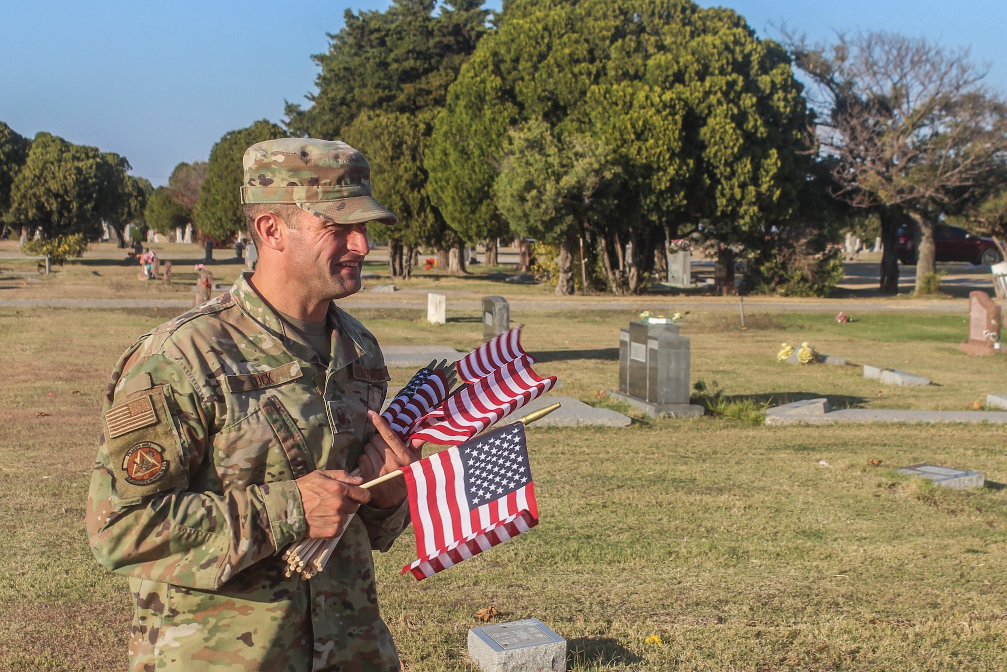 Man holds American flags at a cemetery
