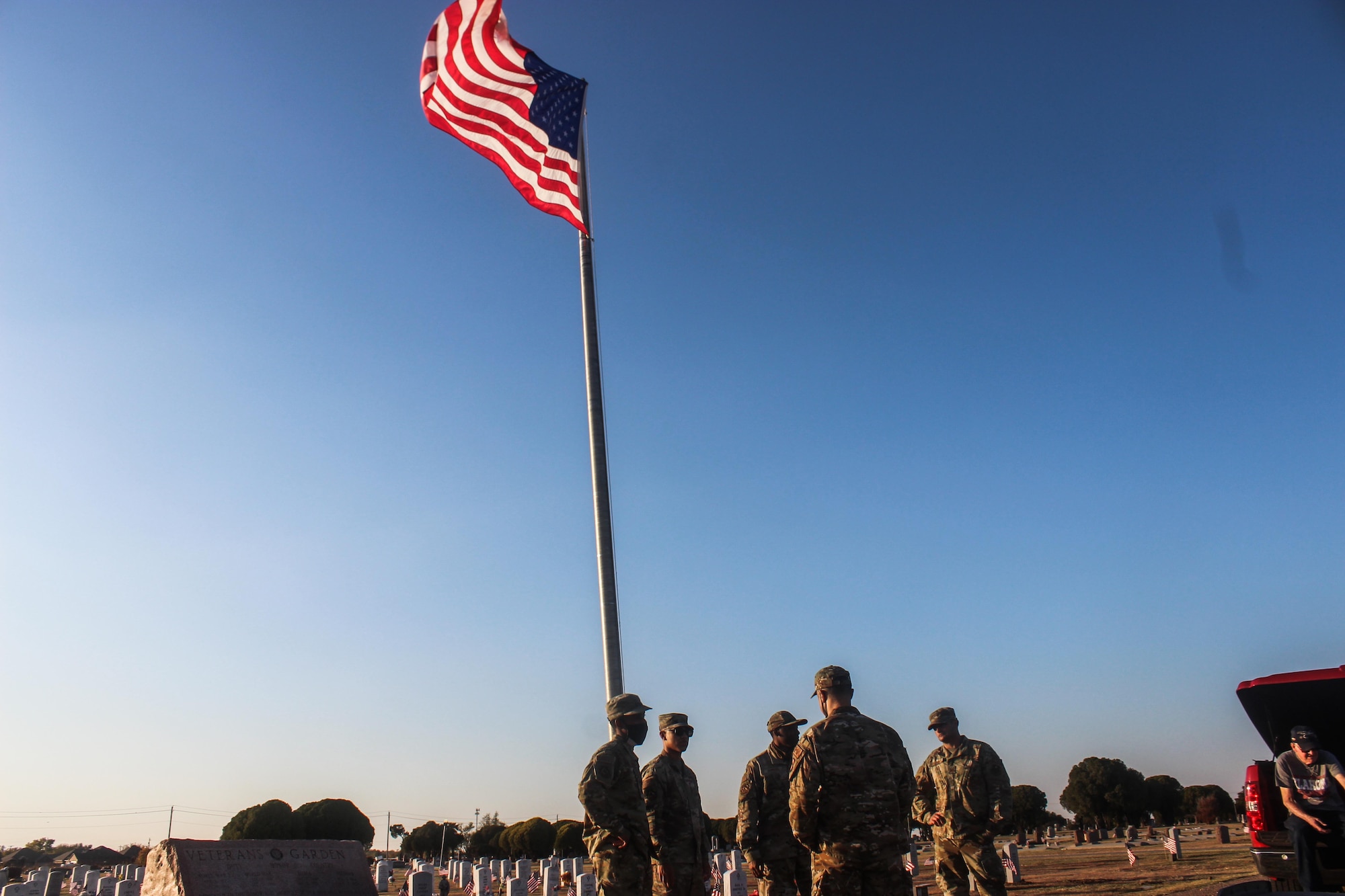 Airmen stand around a large American flag at a cemetery