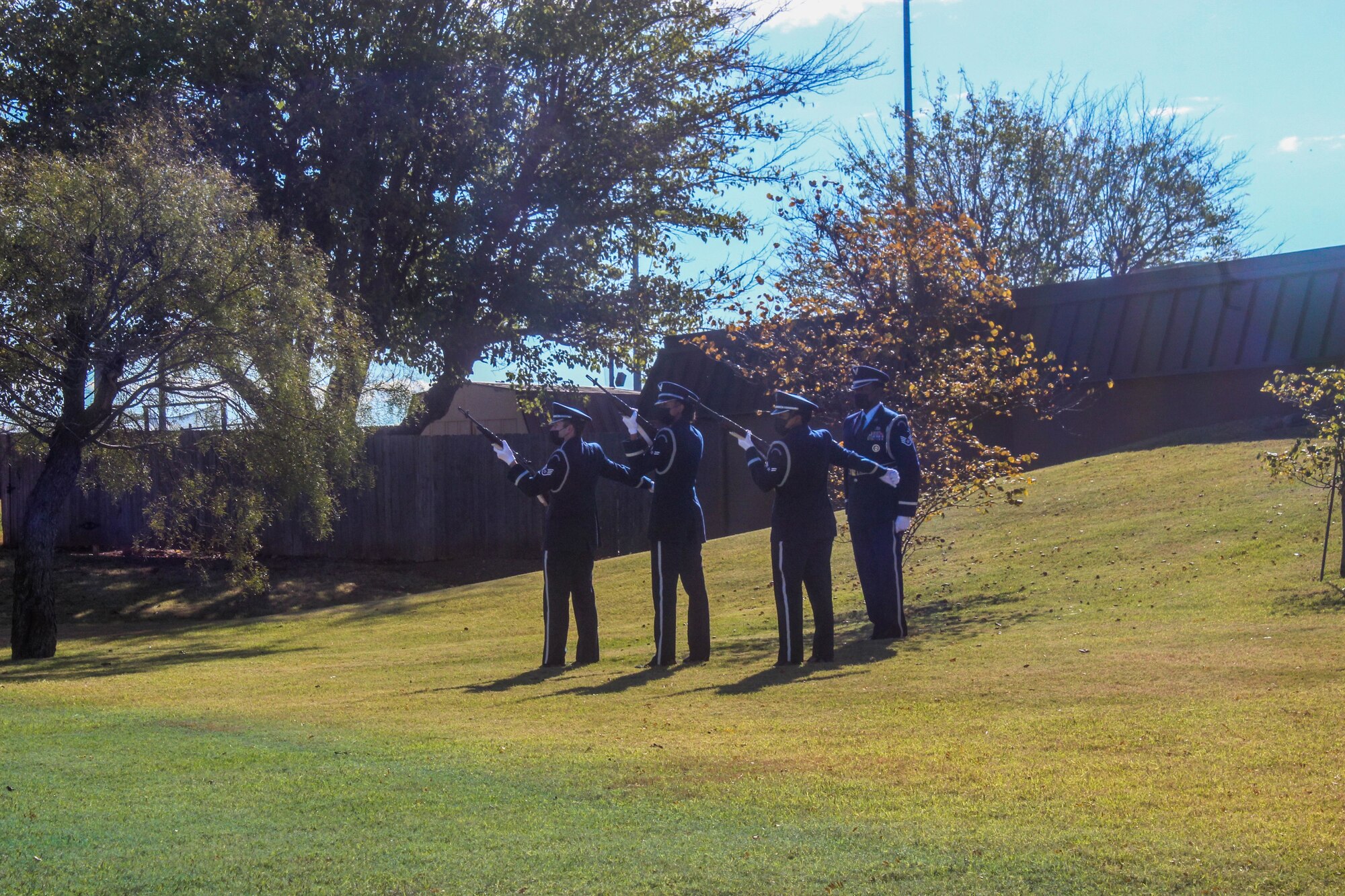 3 airmen ceremonially fire blanks from rifles as a sergeant commands them