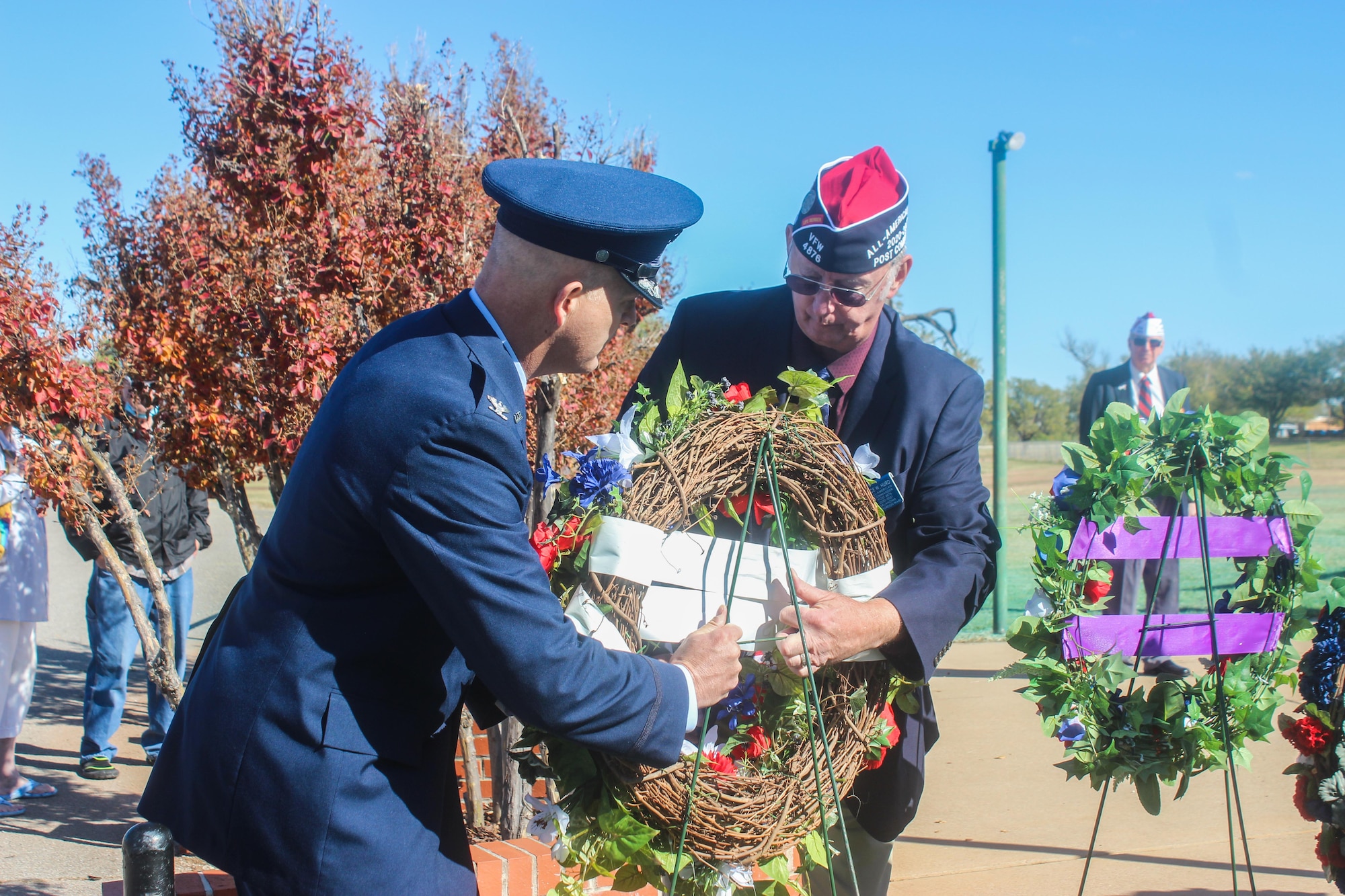 Two men hold a wreath