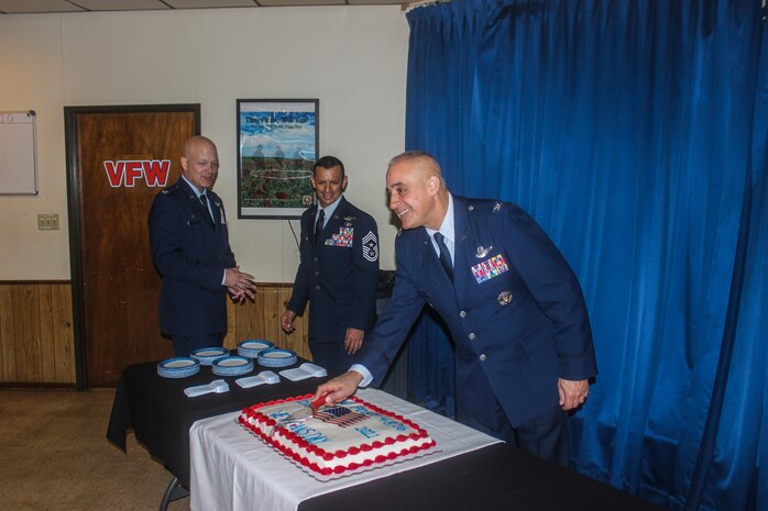 Man cuts cake while two other men look on