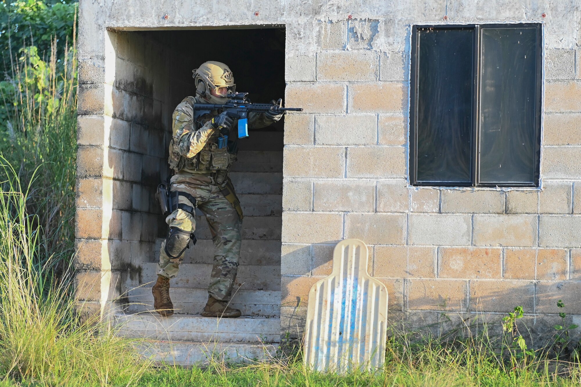 Airman coming down a stairwell and pointing his weapon.