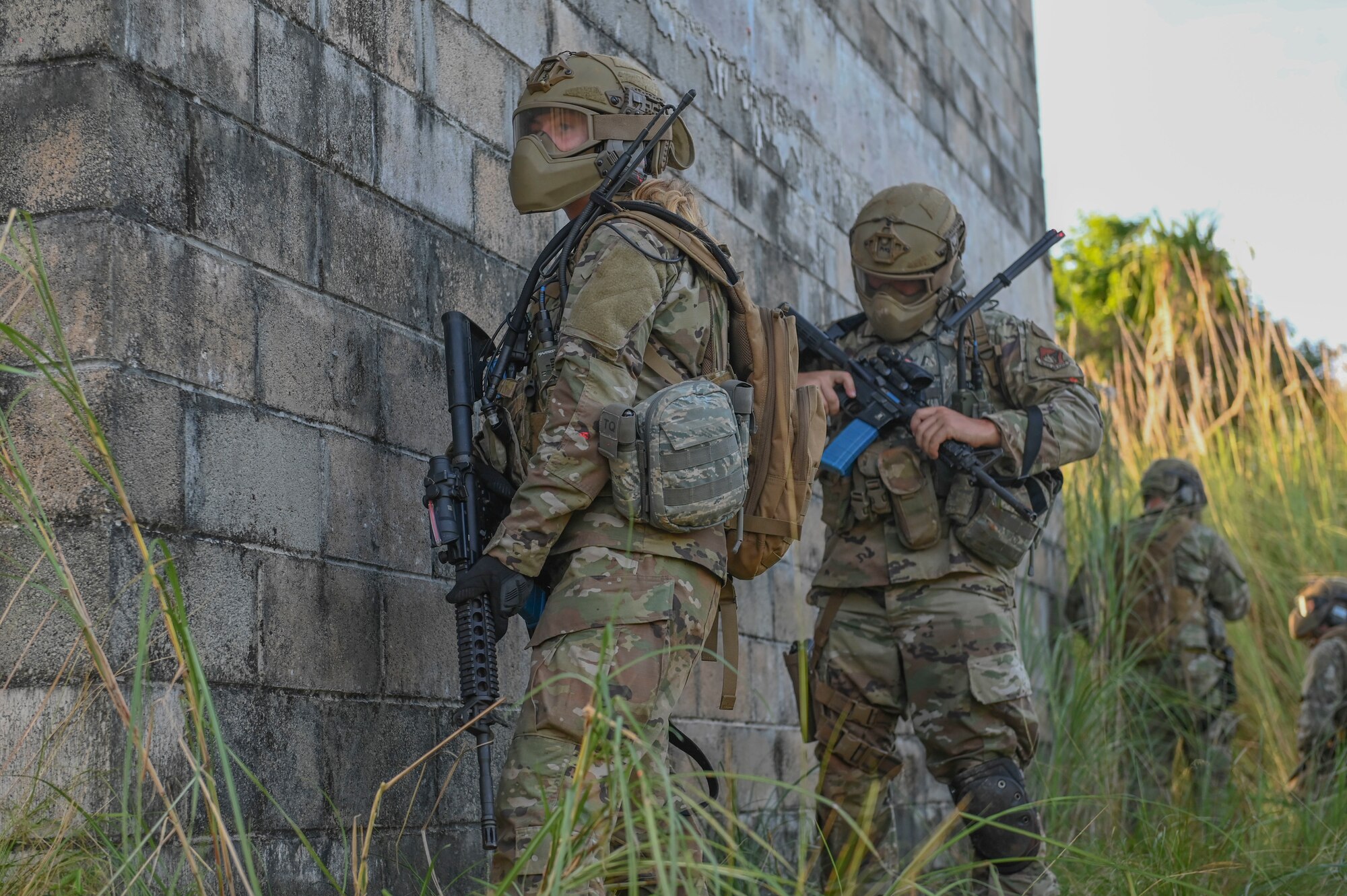 Airmen hiding behind a cement wall.