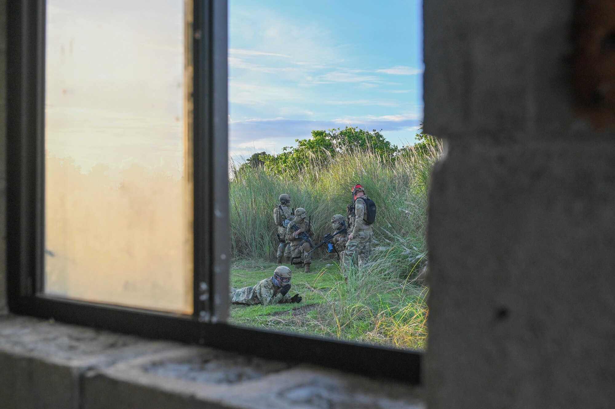 Airmen sitting on the grass through the view of a window