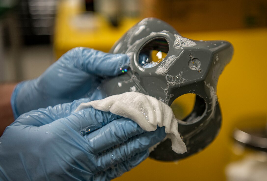 Senior Airman Cameron Nixon, 80th Fighter Squadron aircrew flight equipment technician, disinfects a part of the flight helmet oxygen mask at Kunsan Air Base, Republic of Korea, Nov. 8, 2021. The HGU-55/P flight helmet includes an oxygen mask, night vision goggles and a heads-up display unit, which projects flight information onto the pilot’s visor.  (U.S. Air Force photo Staff Sgt. Jesenia Landaverde)