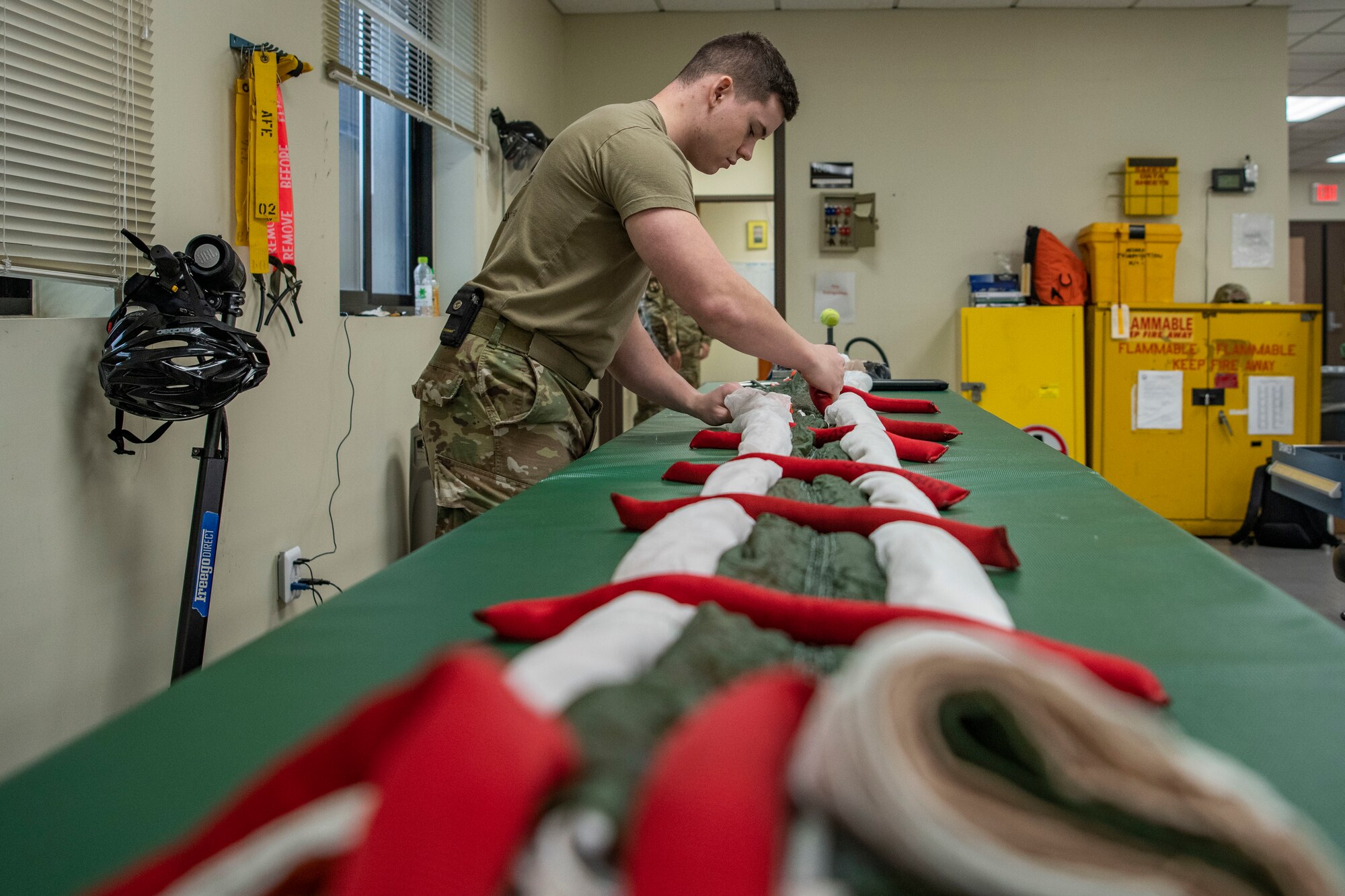 Senior Airman Colton Knight, 8th Operation Support Squadron aircrew flight equipment technician, rolls up a parachute at Kunsan Air Base, Republic of Korea, Nov. 8, 2021. There are AFE Airmen at each Kunsan Air Base flying squadron to provide support to that specific squadron’s mission with instructions on how to inspect and maintain gear. (U.S. Air Force photo Staff Sgt. Jesenia Landaverde)