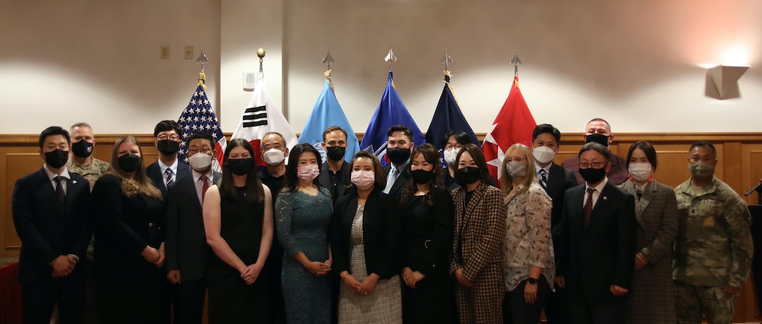 Group of USFK Civilian Employee of the Year awardees facing the camera with Gen. LaCamera and CSM Tagalicud standing in front of a row of flags.