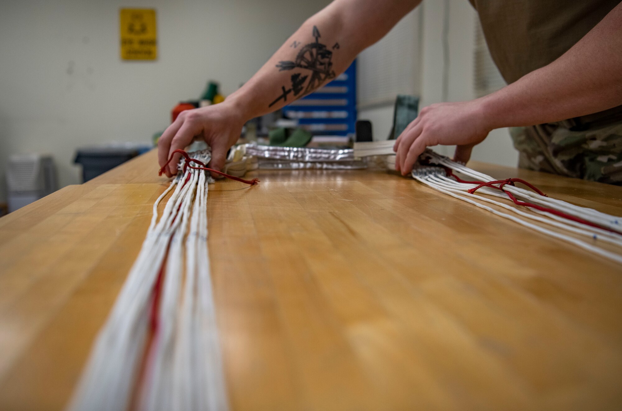 Senior Airman Colton Knight, 8th Operation Support Squadron aircrew flight equipment technician, adjusts parachute strings at Kunsan Air Base, Republic of Korea, Nov. 8, 2021. From packing emergency items like parachutes and survival kits to maintaining regularly used items like oxygen masks, the attention to detail by these Airmen could mean the difference between life and death. (U.S. Air Force photo Staff Sgt. Jesenia Landaverde)