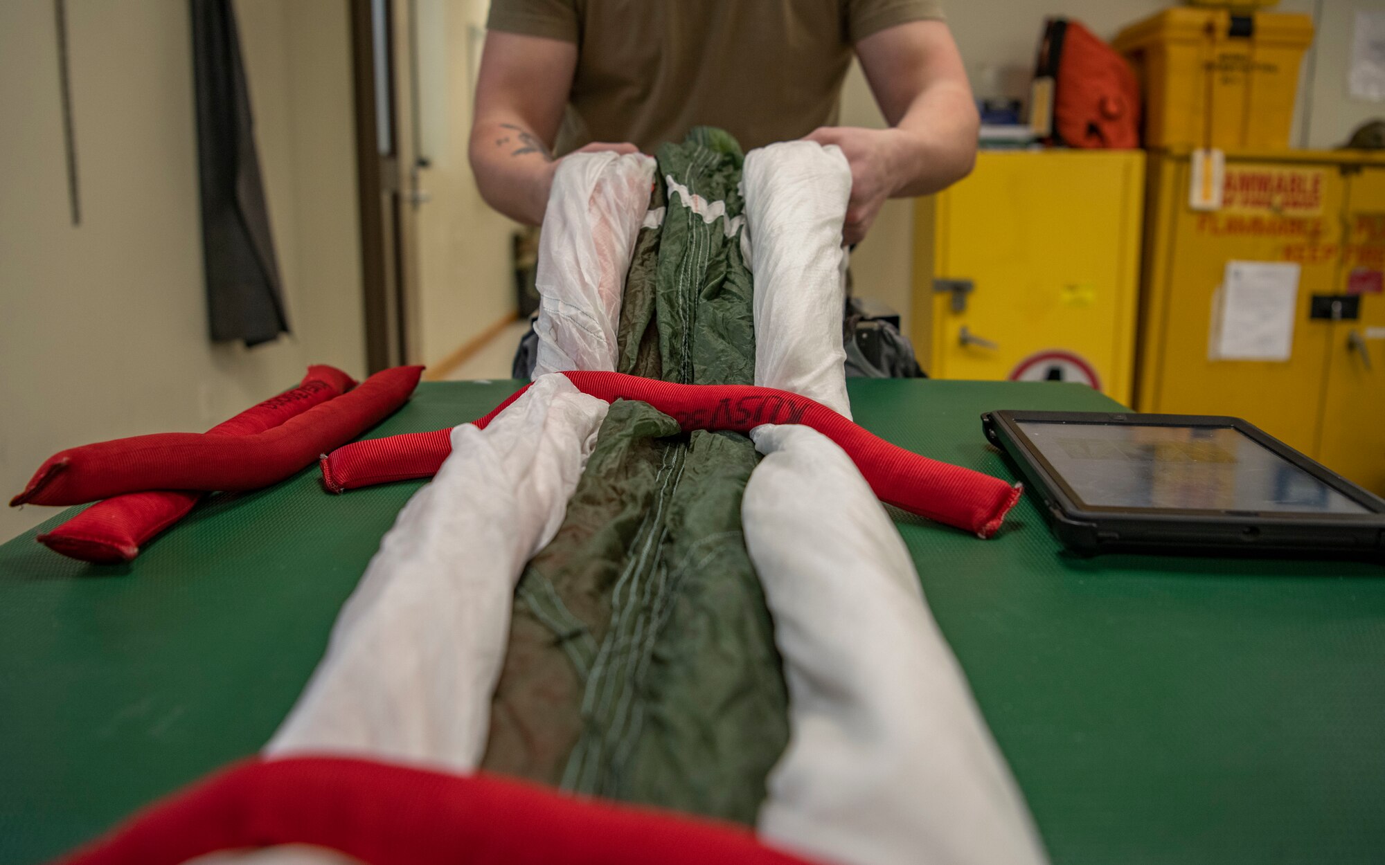 Senior Airman Colton Knight, 8th Operation Support Squadron aircrew flight equipment technician, pulls a parachute at Kunsan Air Base, Republic of Korea, Nov. 8, 2021. From packing emergency items like parachutes and survival kits to maintaining regularly used items like oxygen masks, the attention to detail by these Airmen could mean the difference between life and death. (U.S. Air Force photo Staff Sgt. Jesenia Landaverde)