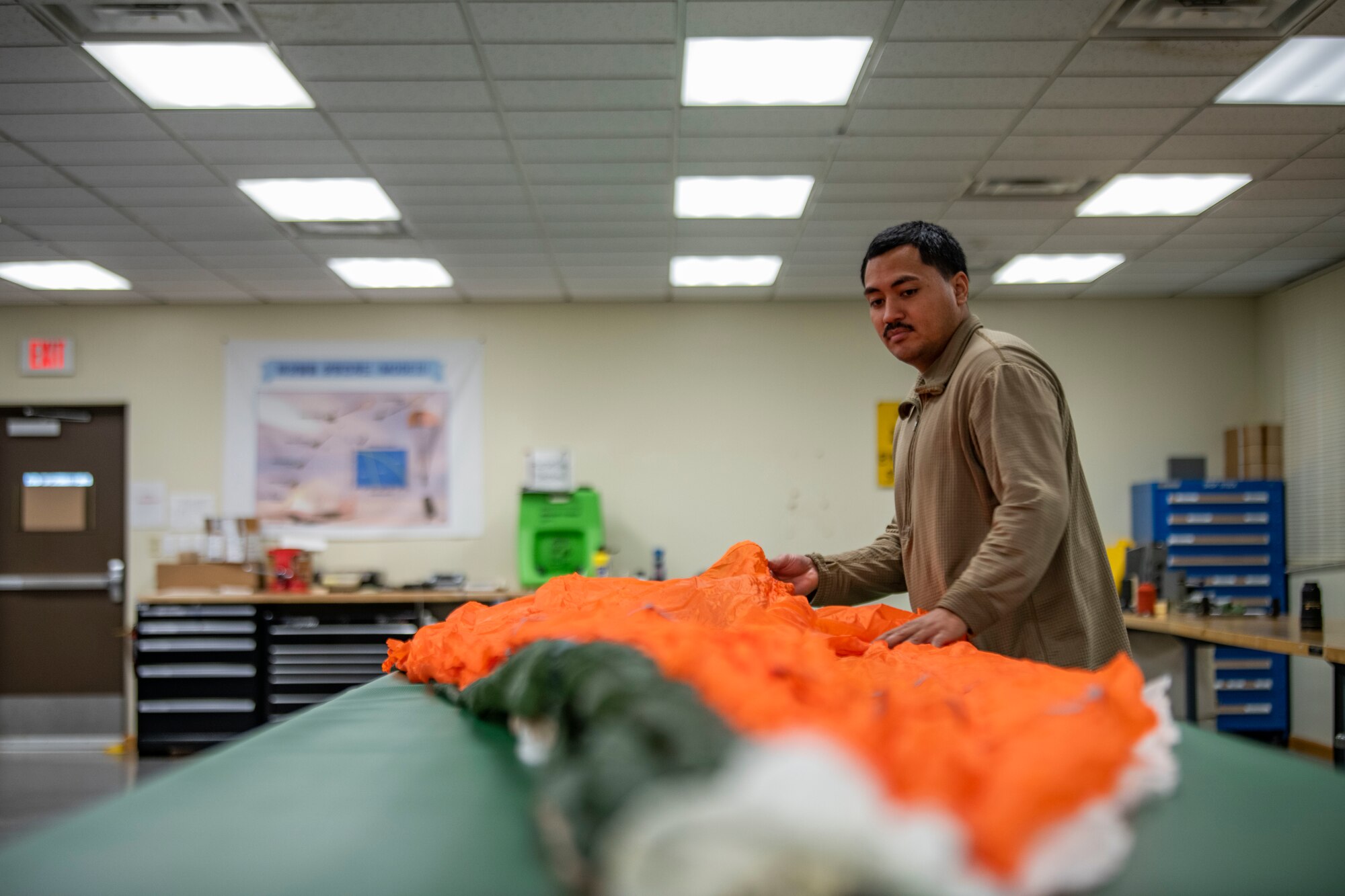 Senior Airman Richard Pena, 8th Operation Support Squadron aircrew flight equipment technician, folds a parachute at Kunsan Air Base, Republic of Korea, Nov. 8, 2021. Aircrew Flight Equipment specialists make sure flyers have the supplies necessary for ensuring that all flight and safety equipment is in the perfect working order.  (U.S. Air Force photo Staff Sgt. Jesenia Landaverde)