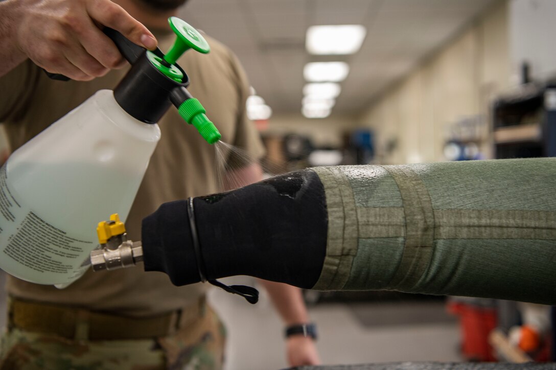 Senior Airman Martin Coetzee, 8th Operation Support Squadron aircrew flight equipment technician, sprays soap solution on an anti-exposure flight dry suit to test for leaks at Kunsan Air Base, Republic of Korea, Nov. 8, 2021. From packing emergency items like parachutes and survival kits to maintaining regularly used items like oxygen masks, the attention to detail by these Airmen could mean the difference between life and death. (U.S. Air Force photo Staff Sgt. Jesenia Landaverde)