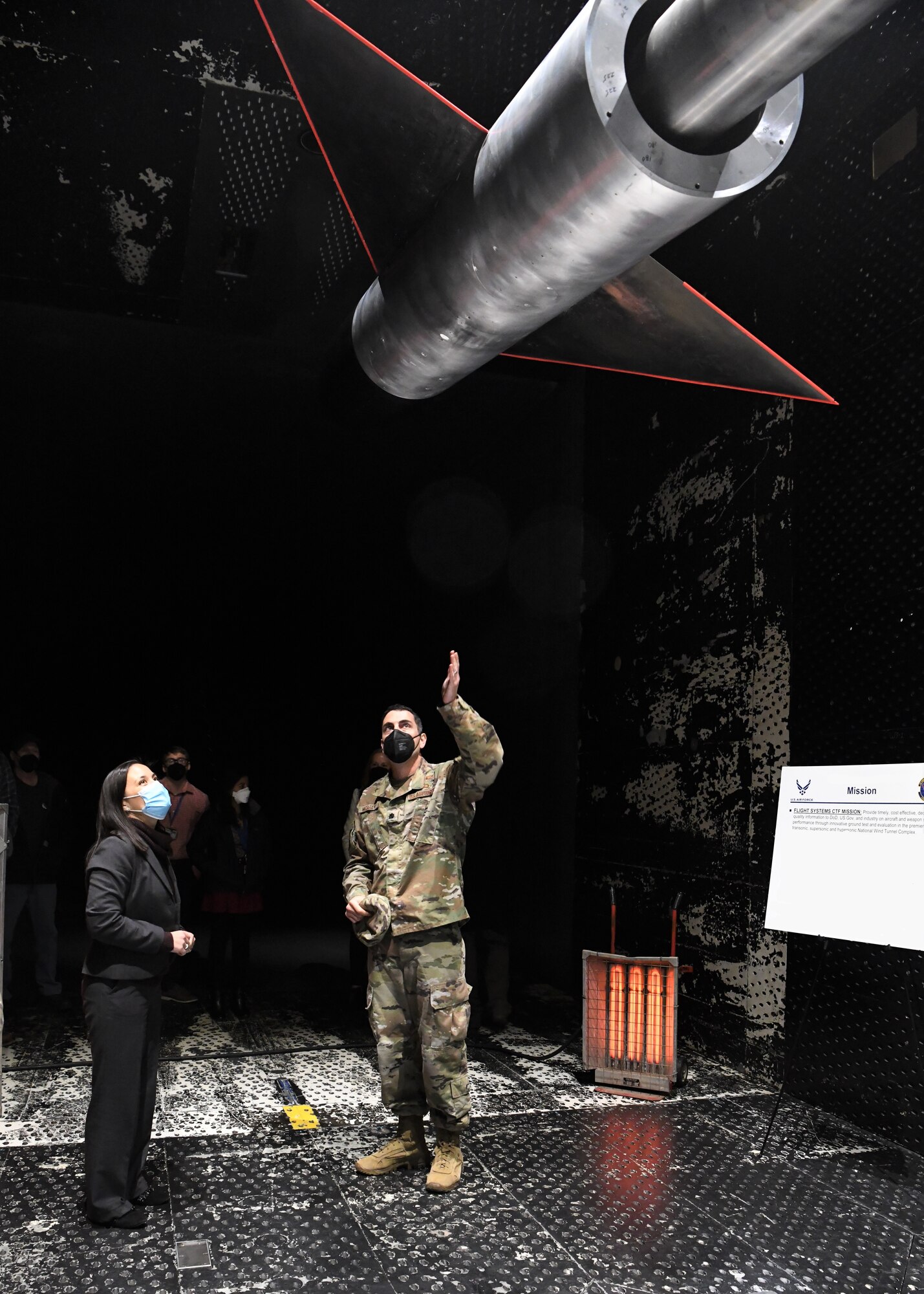 Lt. Col. John McShane, chief of the Aerodynamics Test Branch, Test Division, Arnold Engineering Development Complex (AEDC), speaks with Under Secretary of the Air Force Gina Ortiz Jones about the AGARD-B model installed in the 16-foot transonic wind tunnel at Arnold Air Force Base, Tenn., headquarters of AEDC, Nov. 5, 2021. AGARD models are scalable, generic aerodynamic models that allow for data comparison across different wind tunnels. (U.S. Air Force photo by Jill Pickett) (This image has been altered by obscuring a portion of a poster for security reasons.)