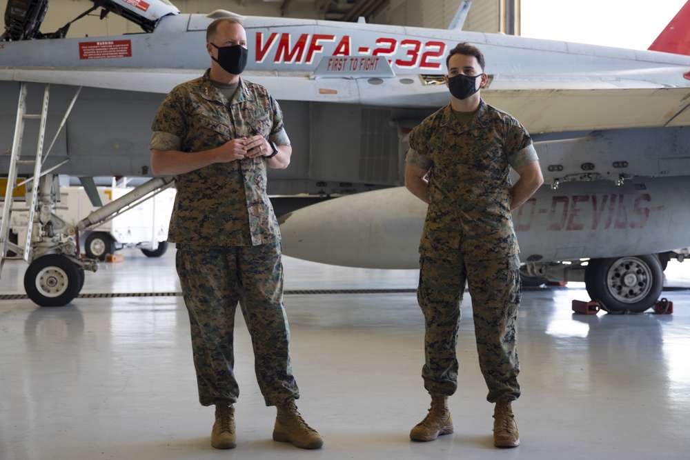 Two Marines talking in front of an airplane.