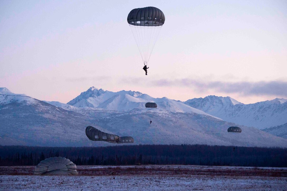 Airmen descend in the sky wearing parachutes.