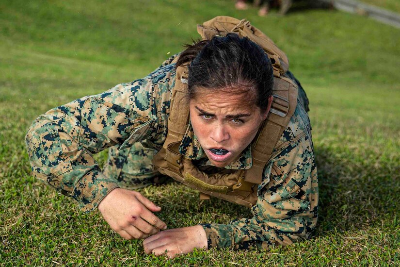 A Marine crawls on grass.