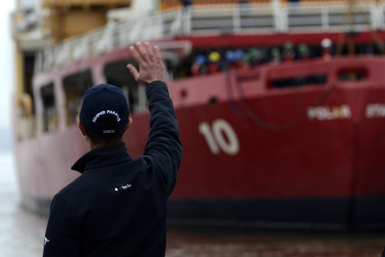 A family member of a Coast Guardsman aboard Cutter Polar Star (WAGB-10) waves as the cutter departs Seattle Saturday, Nov. 13, 2021. The crew of Cutter Polar Star annually supports Operation Deep Freeze, a joint military mission to resupply United States Antarctic stations, by cutting a path through ice as thick as 20 feet so that other support vessels can reach the remote destination. (U.S. Coast Guard photo by Petty Officer 3rd Class Michael Clark)