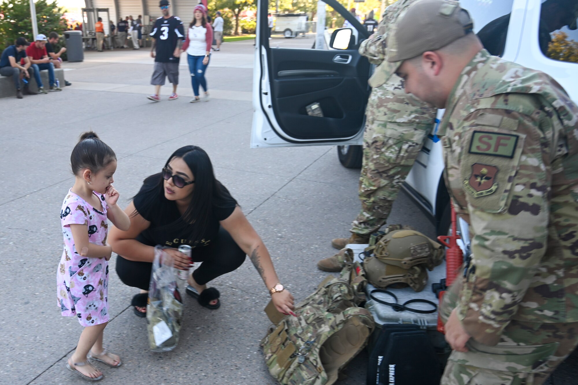 U.S. Air Force Senior Airman Caleb Cool, 56th Security Forces Squadron base defense operator, explains the different types of protective gear used in his career field to a mom and her daughter Nov. 14, 2021, during a Salute to Service event at the State Farm Stadium, Glendale, Arizona.