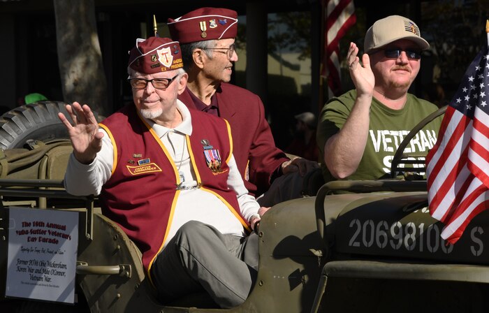 Obie Wickersham, World War II veteran and Korean War POW, left, and others wave to parade onlookers during a Veterans Day Parade Nov. 11, 2021, in Marysville, California.