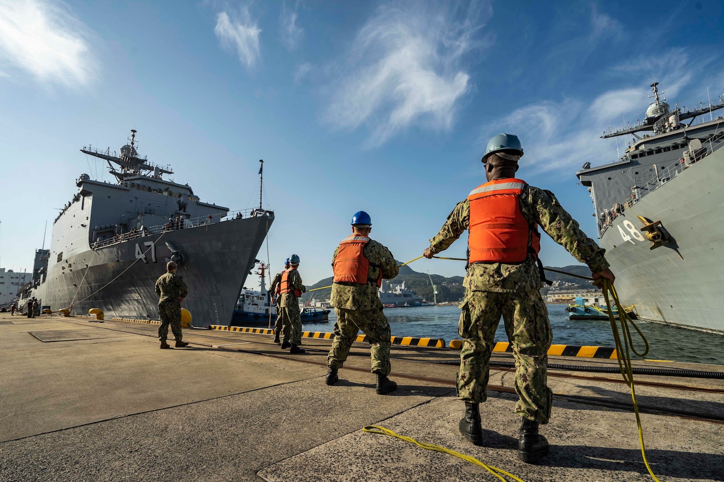 Sailors assigned to Commander, Fleet Activities Sasebo, Japan (CFAS) handle lines as the amphibious dock landing ship USS Rushmore (LSD 47) moors pierside at CFAS Nov. 17, 2021 becoming the newest addition to the forward-deployed naval forces (FDNF). The Rushmore relieves another Whidbey Island-class ship, USS Germantown (LSD 42), which departed Sasebo Sept. 15, 2021 after more than a decade of FDNF service.