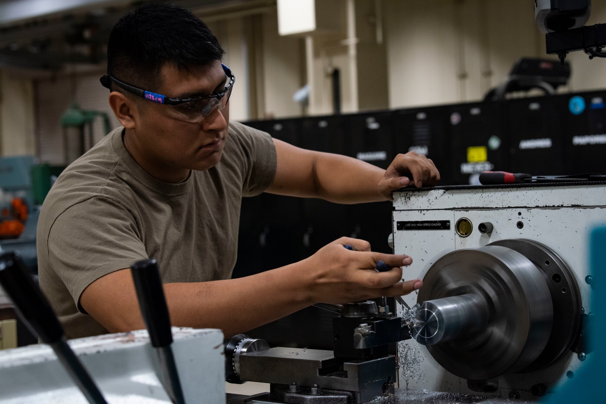 Service member operates a machine to cut metal.