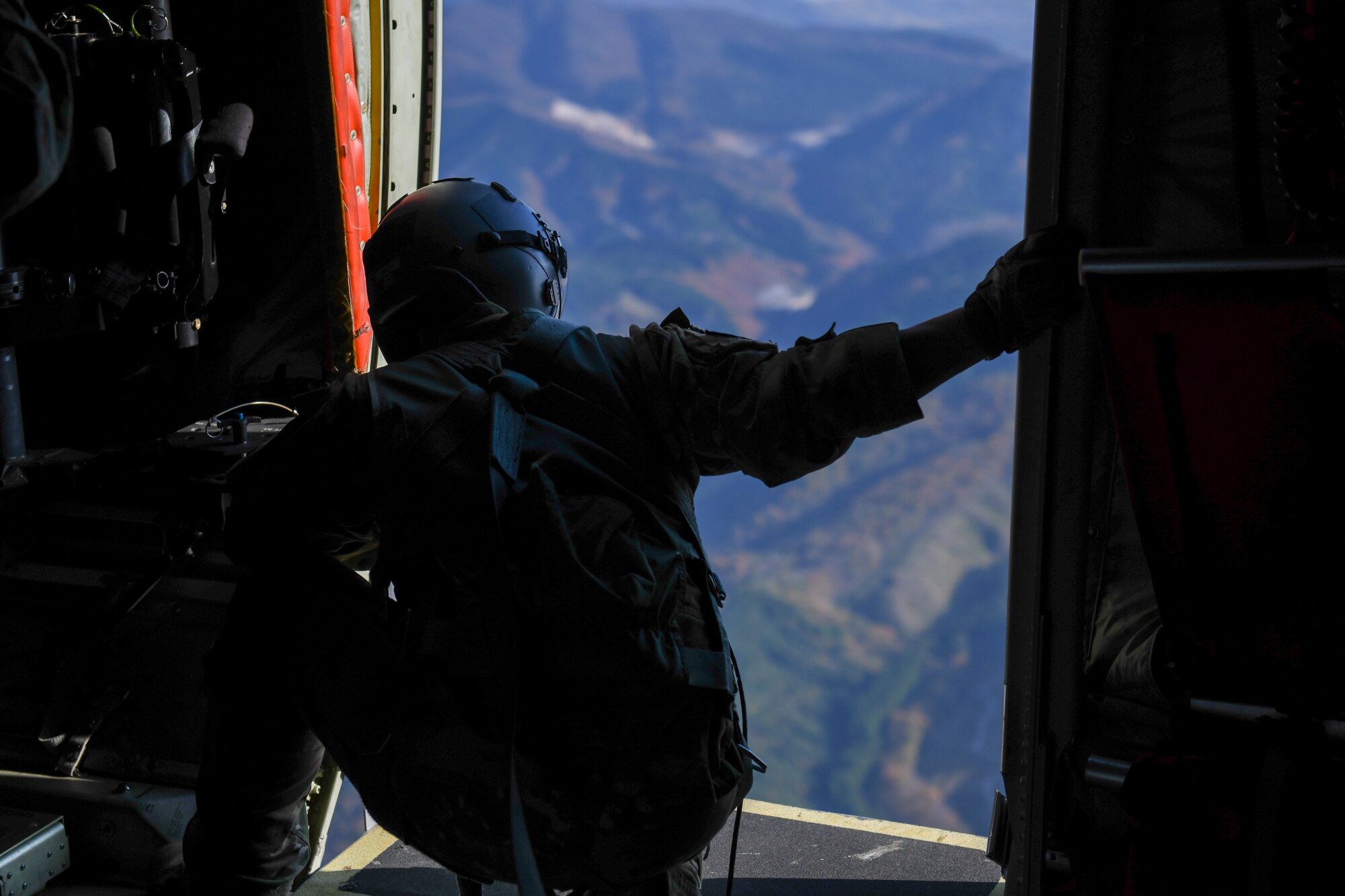 A loadmaster watches Japan Ground Self-Defense Force jumpmasters descend above the Hijudai drop zone