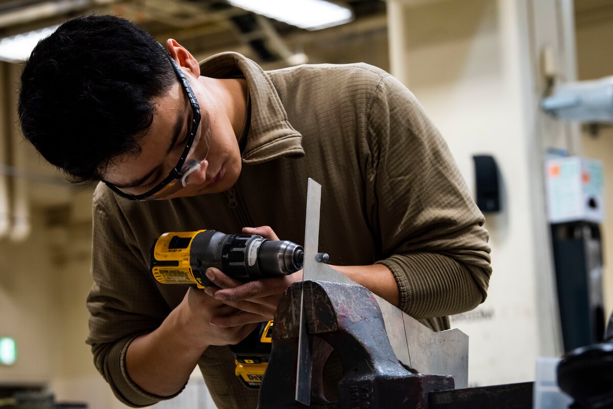 Airman 1st Class Haneul Kwon, 35th Maintenance Squadron aircraft metals technology journeyman, grinds a piece of metal at Misawa Air Base, Japan, Oct. 25, 2021. Kwon is a part of a flight that has implemented the Theory of Constraints (TOC), a mentality shift that improves workflow by removing unnecessary maintenance multitasking, which ultimately reduces the number of aircraft in a “work-in-progress” status.