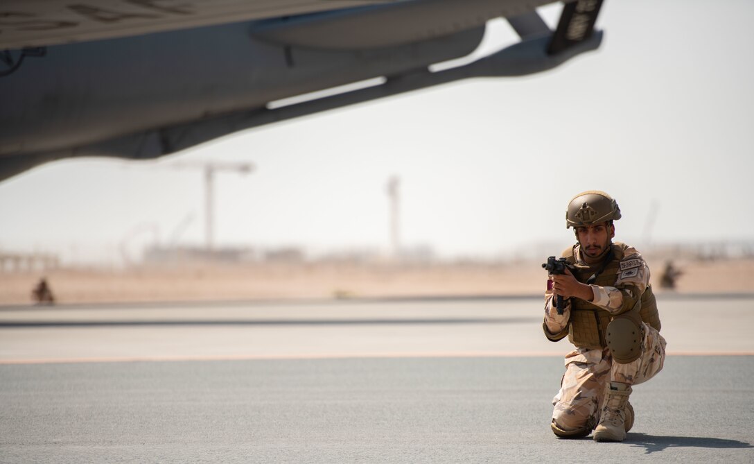 Qatari Emiri Air Force member kneels next to an aircraft for security.