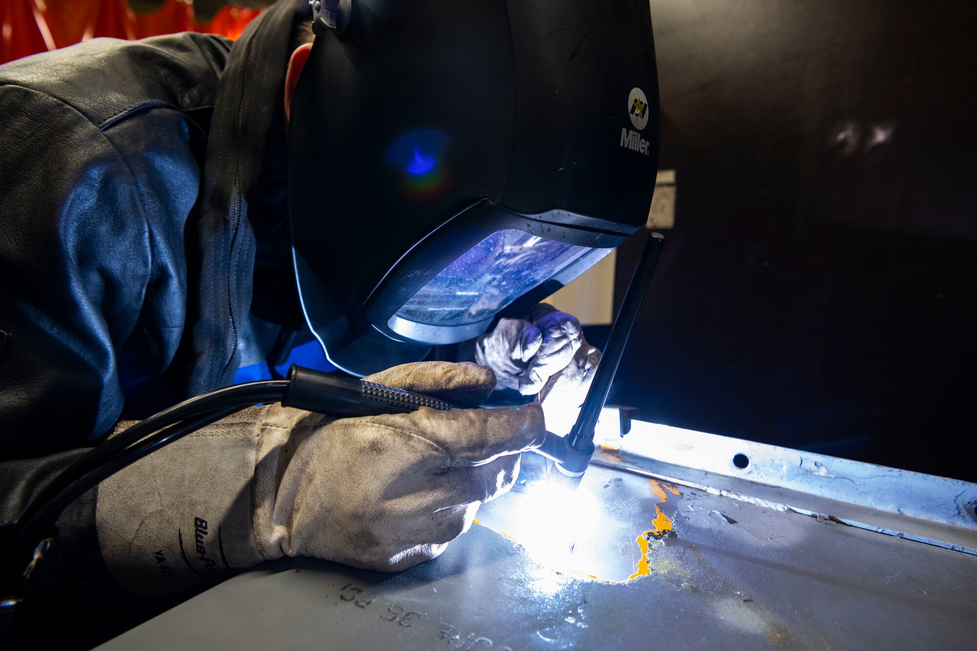 Service member welds pieces of metal.