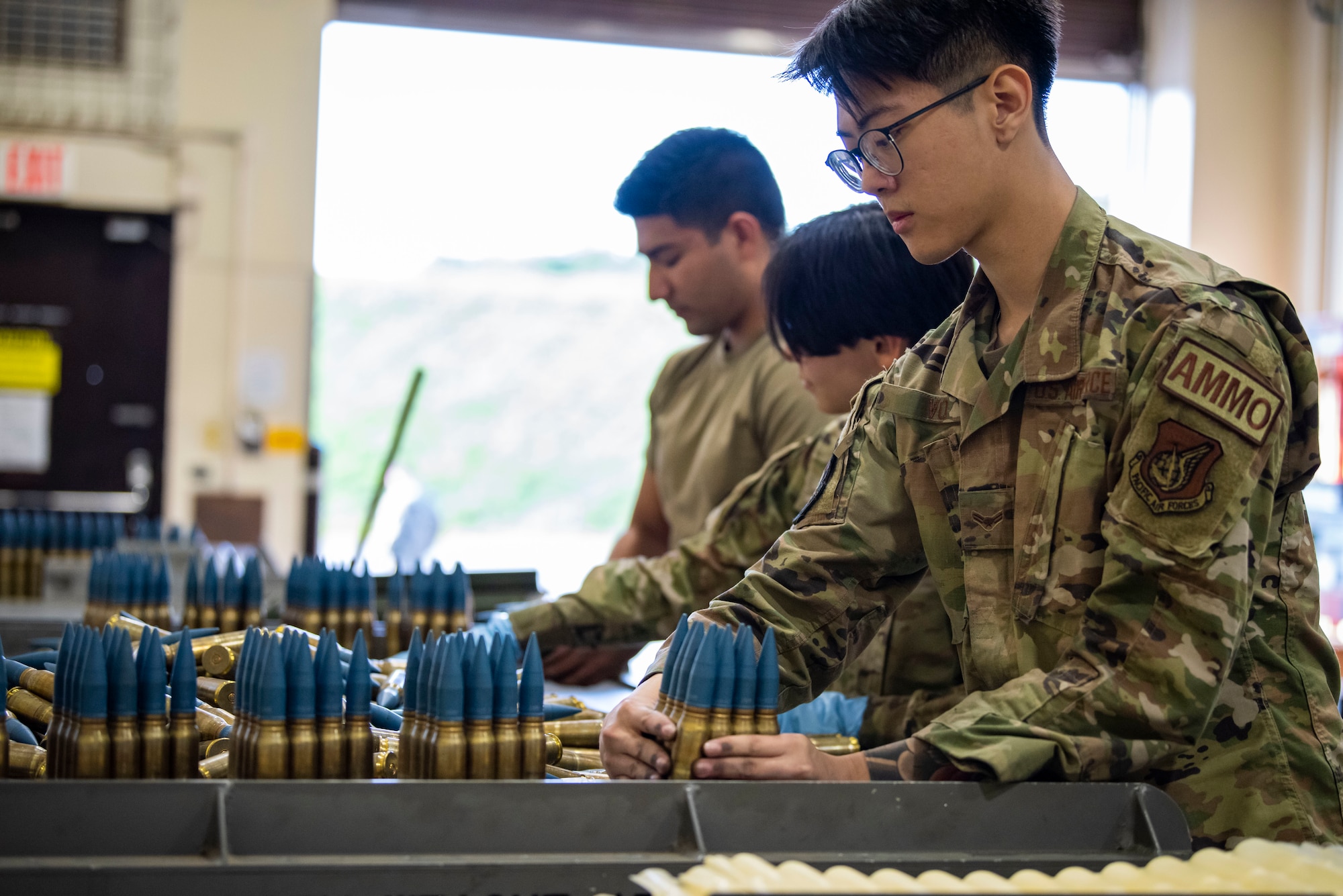 Service members in uniform organize bullets on a table.